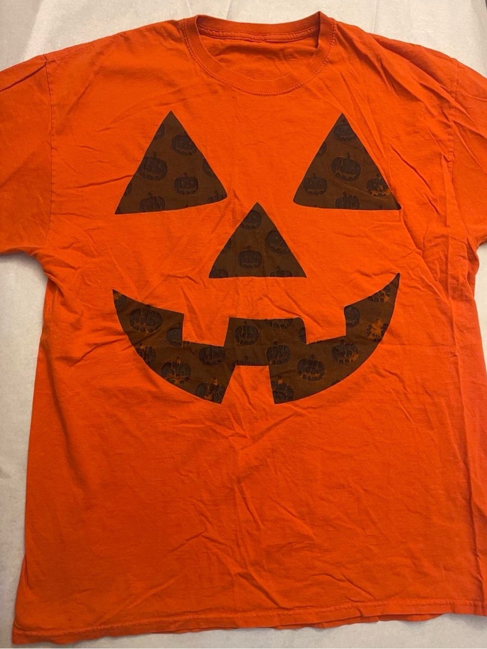 Orange Halloween pumpkin face graphic tee with black jack-o'-lantern face design